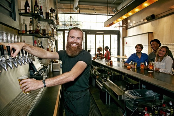Smiling bartender pouring beer at bar