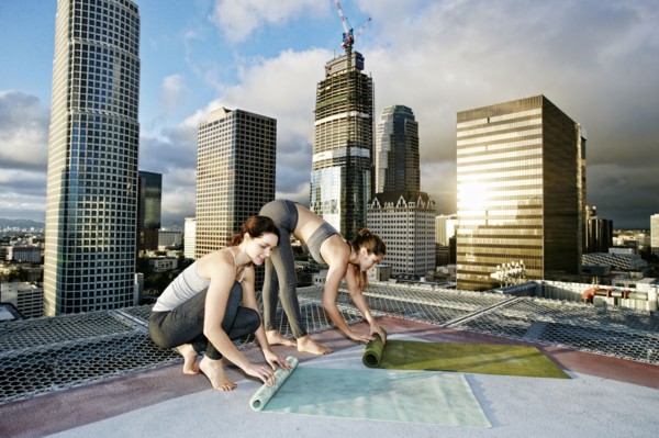 Caucasian women rolling exercise mats on urban rooftop after yoga