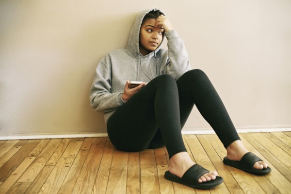Mixed Race woman sitting on floor listening to cell phone