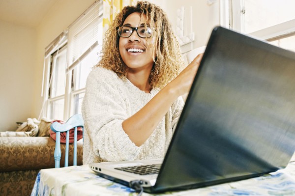Smiling Mixed Race woman using laptop