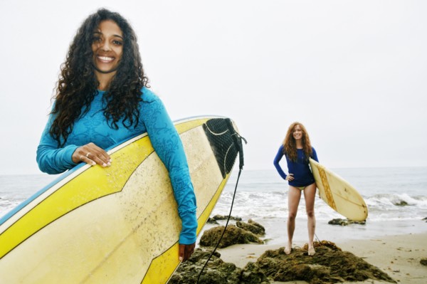 Smiling women holding surfboards at beach