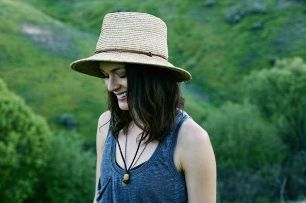 Smiling woman wearing hat on hill