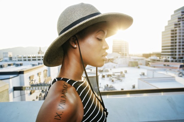 Pensive Black woman wearing sun hat on rooftop
