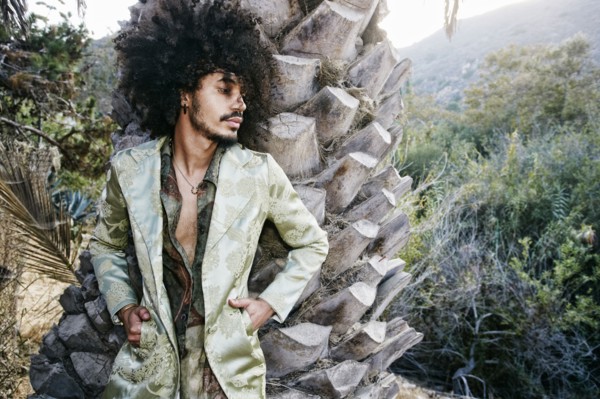 Mixed Race man wearing jacket leaning on tree trunk