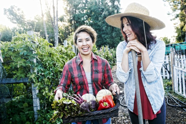 Portrait of women with basket of vegetables in garden
