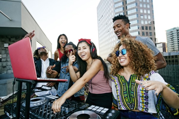 Friends posing with DJ on urban rooftop
