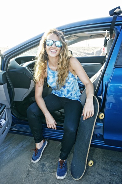 Caucasian woman sitting in car with skateboard