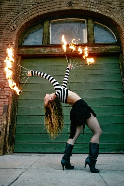 Caucasian woman juggling fire on city sidewalk