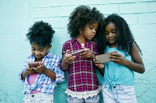 Girls leaning on wall texting on cell phones