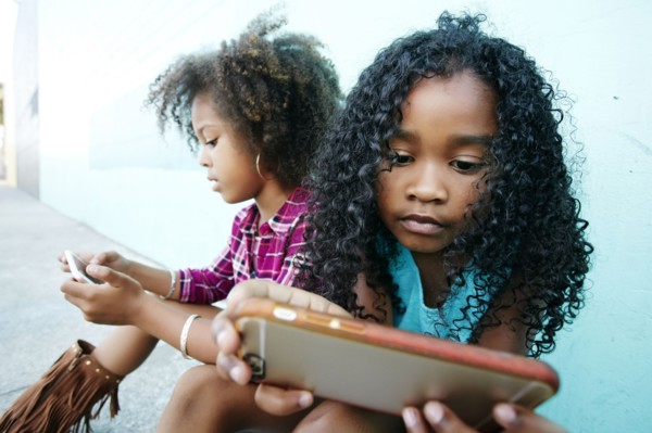 Girls sitting on sidewalk texting on cell phones
