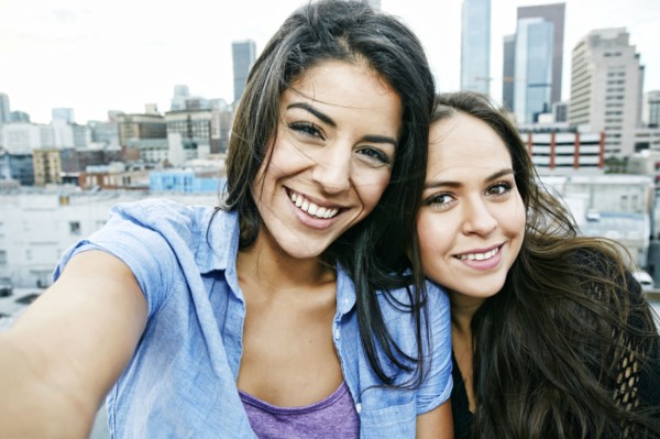 Smiling Hispanic women posing on urban rooftop