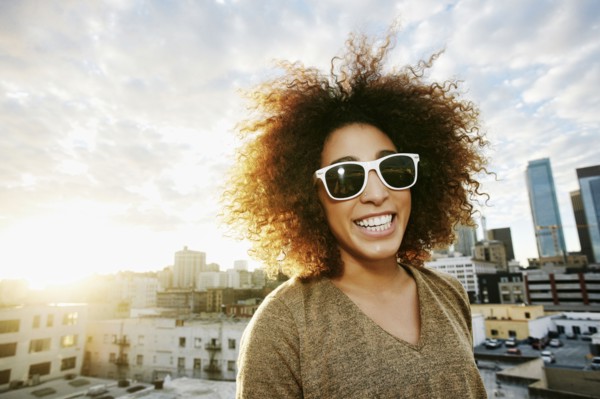 Portrait of smiling Hispanic woman on urban rooftop at sunset