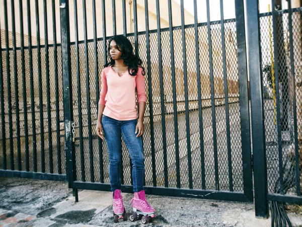 Black woman wearing roller skates near metal gate