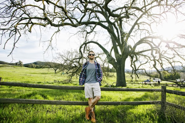 Caucasian man resting on wooden fence