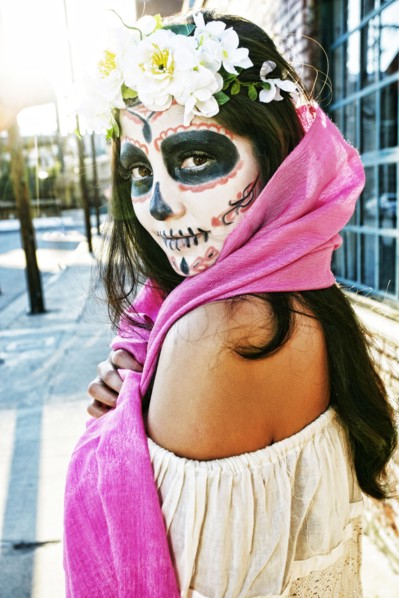 Mixed Race woman on sidewalk wearing scarf and skull face paint
