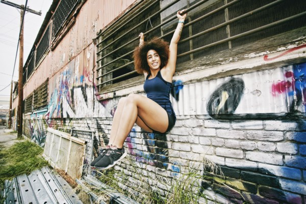 Hispanic woman hanging on bar on graffiti wall