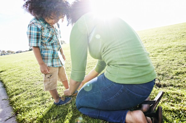 Mixed race mother tying shoe of son