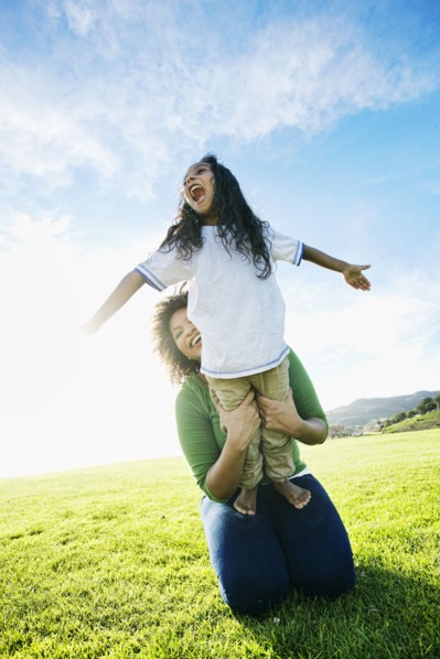 Mixed race mother holding daughter pretending to be airplane