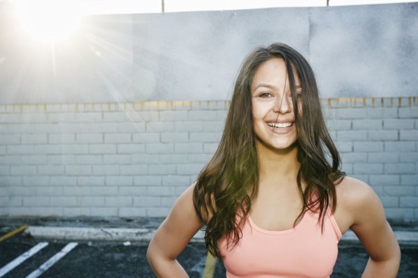 Sunbeams on smiling mixed race woman in parking lot