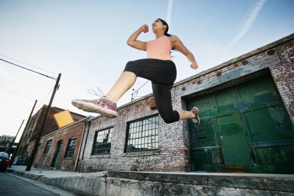 Mixed race woman jumping off loading dock