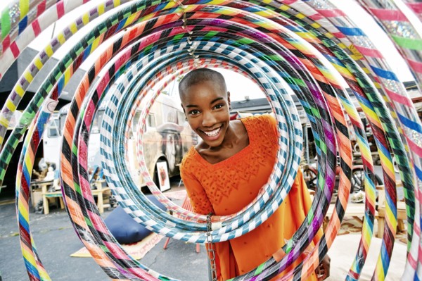Portrait of smiling bald black woman behind hoops