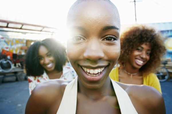 Friends smiling behind bald woman outdoors