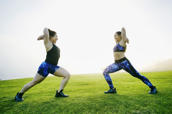 Mixed race women stretching arms in field