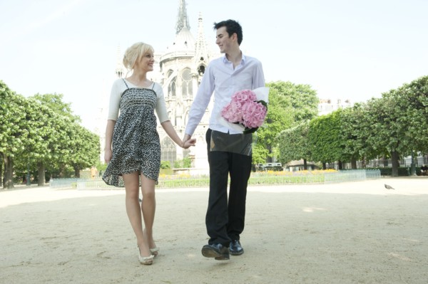 Caucasian couple holding hands in park near Notre Dame