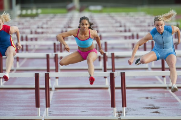 Runners jumping hurdles in race