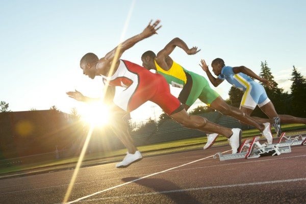 Black runners taking off from starting block in race