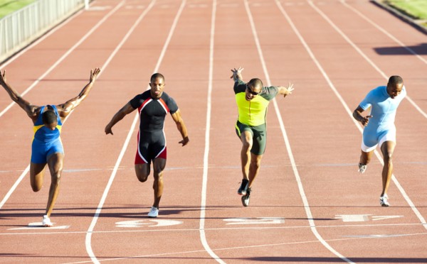 Runners running across finish line on track in race