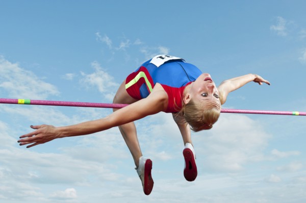 Caucasian athlete jumping over bar