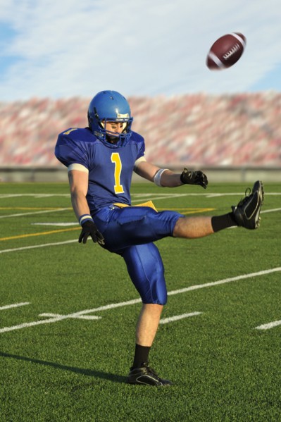 Caucasian football player kicking football