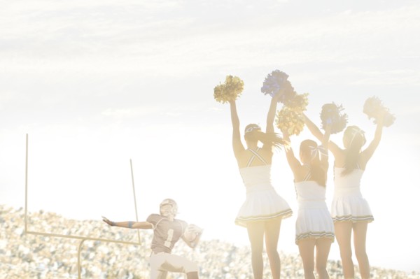 Caucasian cheerleaders on sidelines at football game