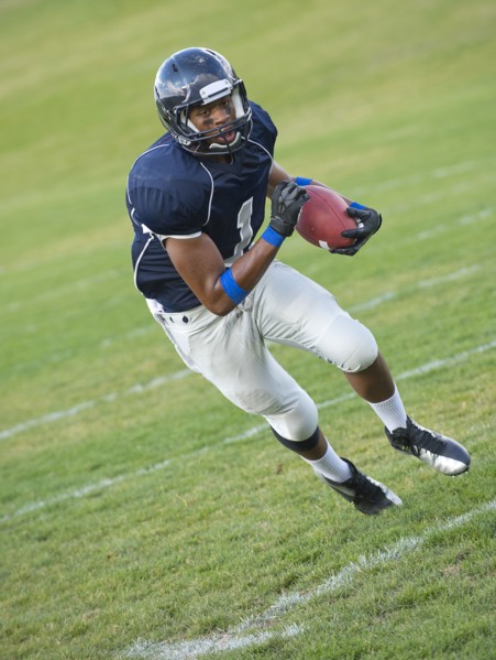 African American football player carrying ball
