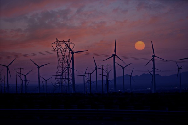 Silhouette of wind turbines and power lines at sunset