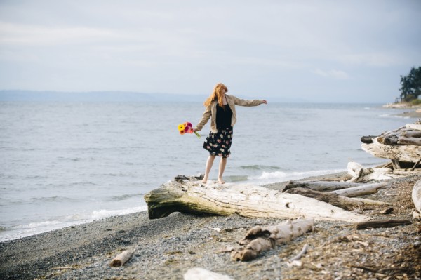 Girl balancing on driftwood on beach