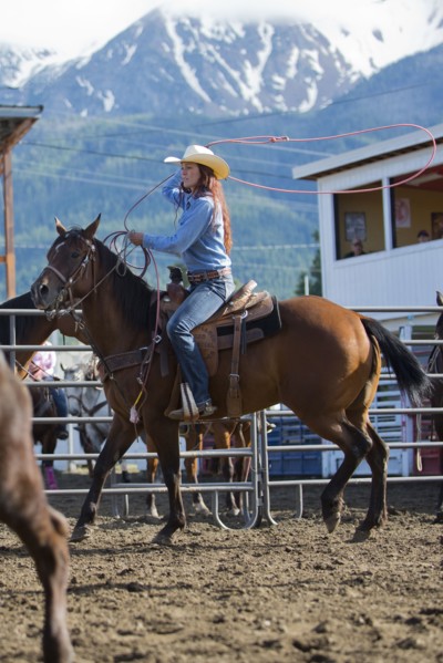 Caucasian cowgirl riding horse in rodeo on ranch