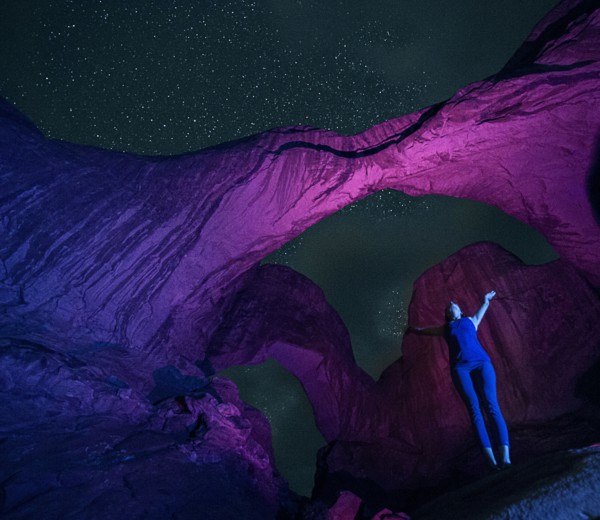 Woman standing in illuminated rocks at night in Arches National Park