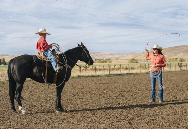 Caucasian woman teaching boy to use lasso on ranch
