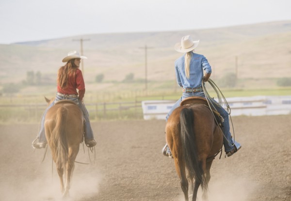 Caucasian cowgirls riding horses on ranch