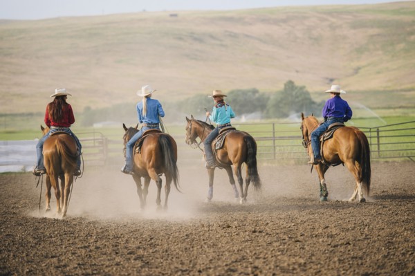 Cowgirls and cowboy riding horses on ranch