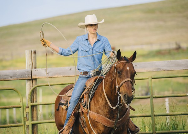 Caucasian cowgirl throwing lasso on horseback