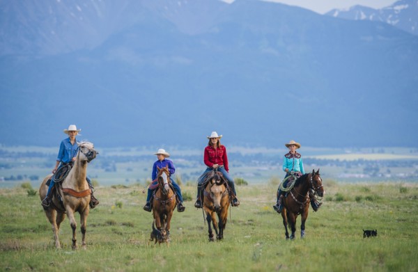 Cowboy and cowgirls riding horseback on ranch