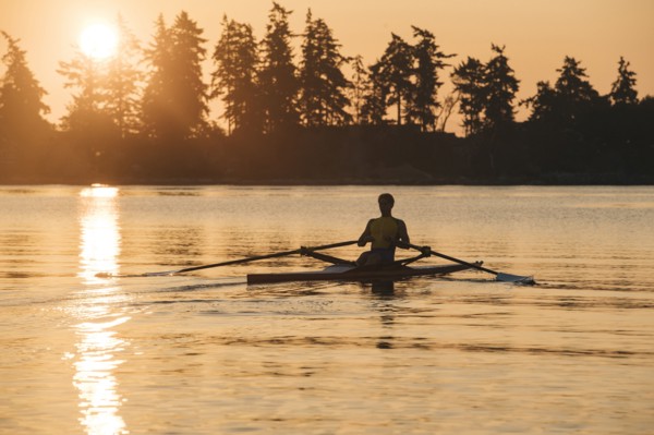 Caucasian man rowing at sunset