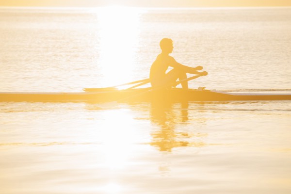 Silhouette of Caucasian man rowing on lake