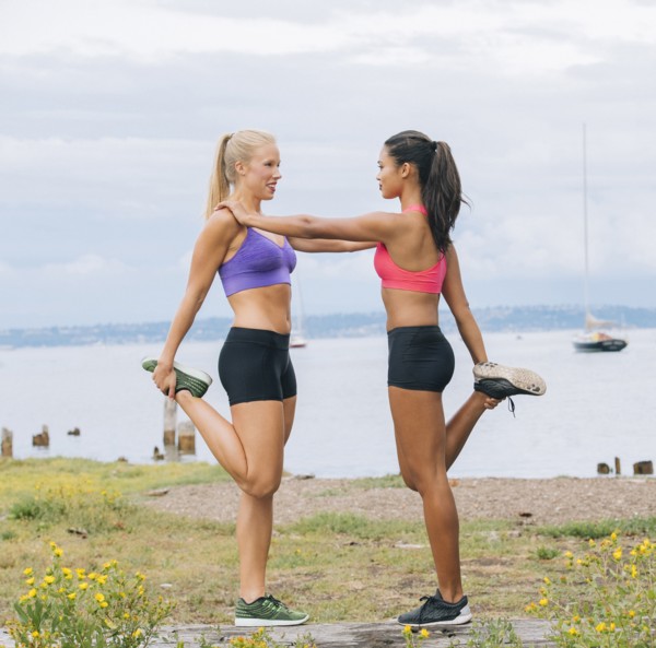 Women stretching legs near lake
