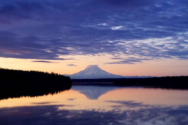 Reflection of clouds and mountain in river at sunset