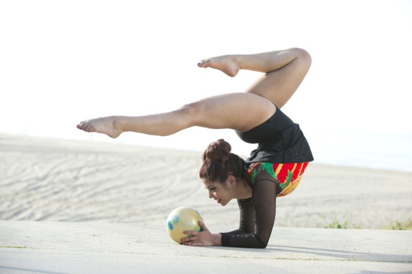 Caucasian gymnast balancing on arms on beach