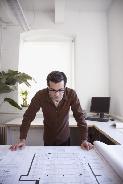 Hispanic businessman looking at blueprints